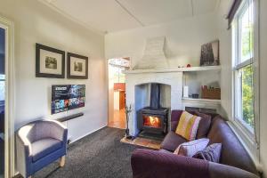 sala de estar con sofá y chimenea en Croft Cottage en Hepburn Springs