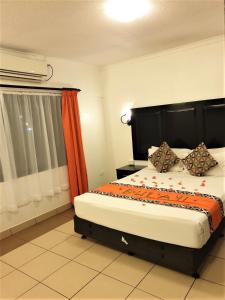 a bedroom with a bed with an orange curtain at Suva Motor Inn in Suva