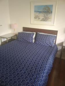 ein Bett mit blauer Decke in einem Schlafzimmer in der Unterkunft Near to Everything Yet in a Rainforest setting in Tewantin