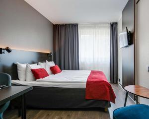 a hotel room with a large bed with red pillows at Best Western Hotel Savoy in Karlstad