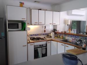 una cucina con armadietti bianchi e frigorifero bianco di Near to Everything Yet in a Rainforest setting a Tewantin