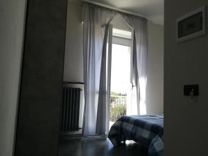 een slaapkamer met een bed en een glazen deur met een raam bij LE MURA Foresteria in Grassobbio