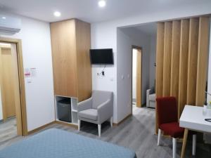 um quarto com uma cadeira e uma televiso na parede em ALOJAMENTO GIRASSOL - Guest House - Quarto com casa de banho privativa em Castelo Branco
