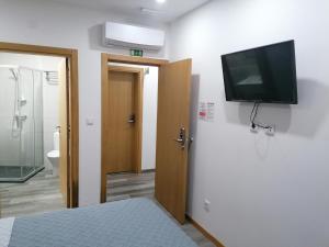 Uma televiso e/ou sistema de entretenimento em ALOJAMENTO GIRASSOL - Guest House - Quarto com casa de banho privativa