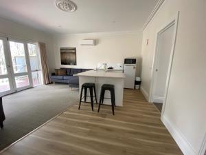 uma cozinha e sala de estar com uma mesa e dois bancos em Campaspe Lodge em Echuca