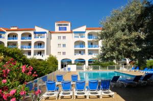 a hotel with blue chairs and a swimming pool at Résidence Goélia Le Grand Bleu in Le Barcarès