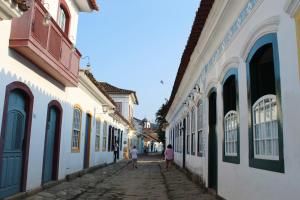 two people walking down a cobblestone alley with buildings at Casa da Matriz Centro Histórico in Paraty