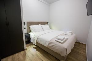 1 dormitorio con 1 cama blanca y 2 toallas en Raise Acropolis View Suites, en Atenas