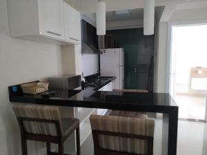 a kitchen with a black counter top and chairs at Vivendas Summer Beach Apto Particular in Bombinhas