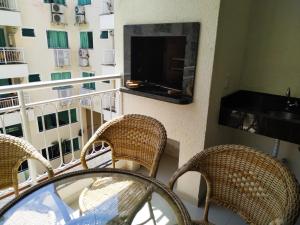 un balcon avec des chaises en osier et une télévision sur un immeuble dans l'établissement Vivendas Summer Beach Apto Particular, à Bombinhas 5 autres photos