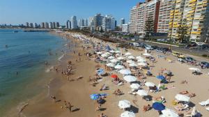 een groep mensen op een strand met parasols bij Apartamento en Edificio Vanguardia in Punta del Este