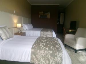 a hotel room with two beds and a chair at Hotel Salento Plaza in Salento
