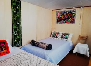 a bedroom with two beds and a painting on the wall at Uros Suma Jakaa Lodge Titicaca Experience in Puno