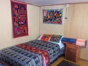 a small room with a bed and paintings on the wall at Uros Suma Jakaa Lodge Titicaca Experience in Puno