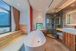 baño grande con bañera grande y lavamanos en Enshi Grand Canyon Yutan Muyun Guesthouse, en Enshi