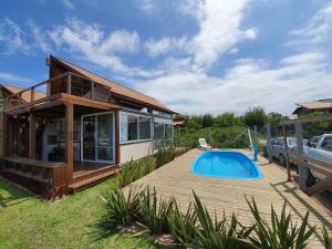 a house with a swimming pool next to a deck at Descanso do Rosa - cabanas charmosas in Imbituba