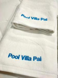 a stack of white towels with blue writing on them at Pool Villa Banana House Pai in Pai