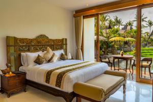 a bedroom with a bed and a patio with a table at Menzel Ubud in Ubud