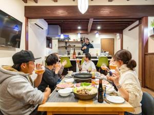 un grupo de personas sentadas alrededor de una mesa comiendo comida en Wow! KANAZAWA STAY, en Kanazawa