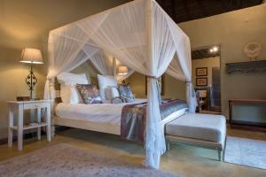 a bedroom with a canopy bed and a chair at Kambaku Safari Lodge in Timbavati Game Reserve