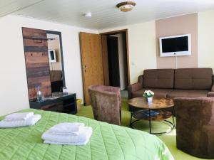 a living room with a green bed and a couch at Hotel Restaurant Oberland in Neuhaus am Rennweg