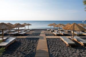 una spiaggia con sedie a sdraio, ombrelloni e l'oceano di Kamari Beach Hotel a Kamari