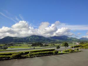 a view of a road with mountains in the background at Shikino Mori in Minami Aso