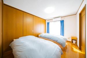 1 dormitorio con 2 camas y ventana en Hachijyo-island Blue Eight -八丈島ブルーエイト-, en Mitsune