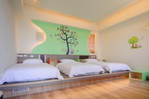 two beds in a room with a tree mural on the wall at So Lohas B&B in Beigan