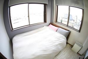 a small bedroom with a white bed and two windows at ロワジール岩槻301 in Iwatsuki