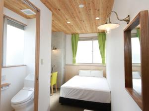 a small bedroom with a bed and a toilet at Hiroshima Peace Hotel in Hiroshima