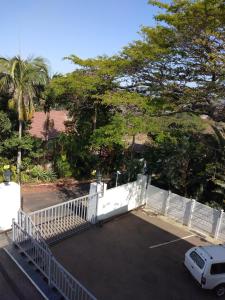 un coche aparcado en un estacionamiento con una valla blanca en Singatha Guesthouse en Durban