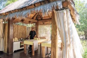 een man in een huis met rieten dak en een tafel bij Jabulani Safari in privé-wildreservaat Kapama
