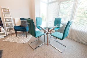 a dining room with a glass table and blue chairs at The Harrogate Abode in Harrogate