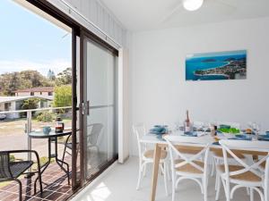 a room with a balcony with a table and chairs at Krait Court, 1 6-8 Krait Cl - great 2 bedroom unit close to little beach in Nelson Bay
