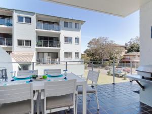 a balcony with a table and chairs and a building at Krait Court, 1 6-8 Krait Cl - great 2 bedroom unit close to little beach in Nelson Bay
