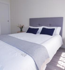 ein großes weißes Bett mit blauen und weißen Kissen in der Unterkunft NICORÉS in Irún