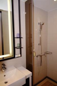 a bathroom with a shower, sink, and mirror at Uinn Business Hotel-Shihlin in Taipei