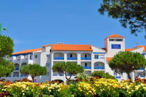 a large white building with an orange roof at Résidence Goélia Le Grand Bleu in Le Barcarès +10 photos