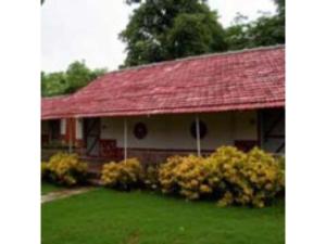 een huis met een rood dak en groen gras bij Annapoorna Farms Villa 6Bhk in Khopoli