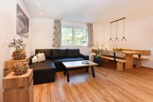 a living room with a black couch and a table at Ferienwohnung Saxenhammer in Vandans