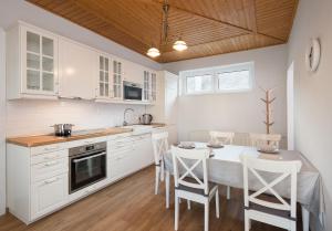 a kitchen with white cabinets and a table and chairs at Provence Apartmanok in Visegrád
