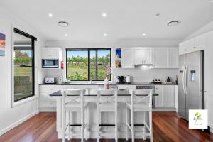 a kitchen with white cabinets and a large island with bar stools at iyla Estate in Pokolbin