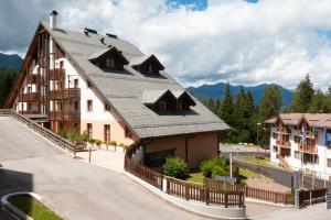 un gran edificio con techo de metal en una calle en Nevesole Folgarida Resort Aparthotel, en Dimaro