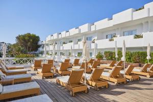 a row of lounge chairs and umbrellas on a patio at a hotel at Hotel Rocamarina - Adults Only in Cala d´Or
