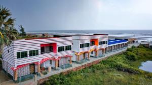 a building on the beach next to the ocean at Resort Garden Retreat Seaview in Mandarmoni