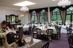 un comedor con mesas, sillas y lámparas de araña en Oakwood Hall Hotel, en Bingley