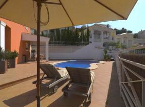 two chairs under an umbrella next to a swimming pool at Villa Melissa - Plusholidays in Calpe