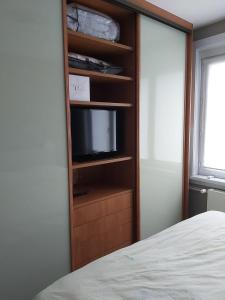 een slaapkamer met een tv in een houten boekenplank bij Appartement met zeezicht in Blankenberge