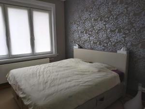 a bedroom with a white bed with a floral wallpaper at Appartement met zeezicht in Blankenberge
